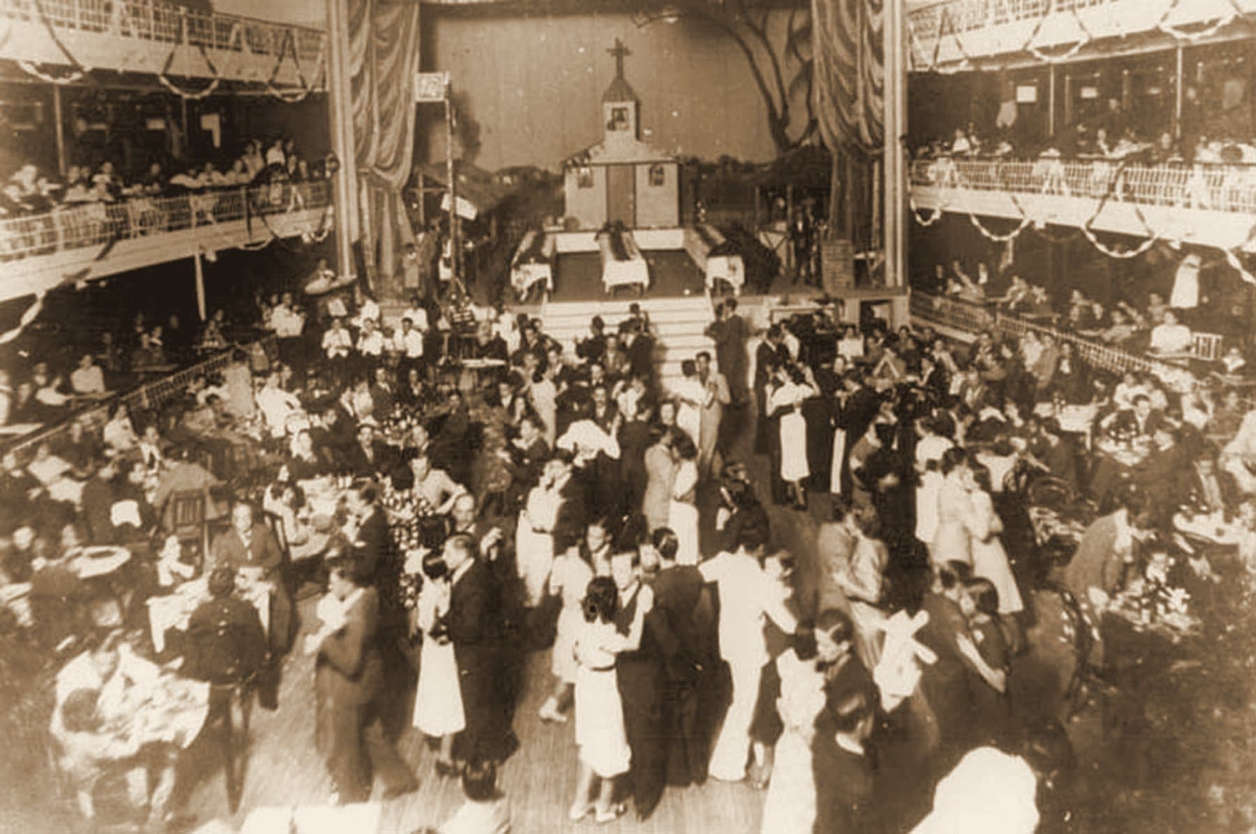 Um grande baile nos anos 1930 — a plateia esvaziada de cadeiras virou salão de dança sob os camarotes decorados.